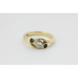 An emerald and diamond three stone crossover ring, rubover set in 18ct yellow gold