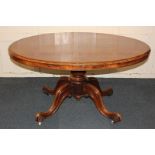 A Victorian walnut oval tilt-top table, on baluster carved stem and four outswept legs on scroll