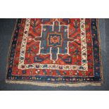 A Persian wool runner carpet with five central geometric motifs within floral multi-line borders, in