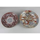 A Japanese porcelain circular dish decorated with white prunus blossom on red ground with circular