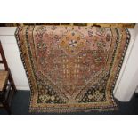 A Persian wool rug, the central floral motif within multi-line borders, in pink, green and brown,