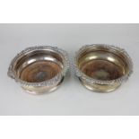 A pair of silver plated bottle coasters with cast scroll and gadrooned border and turned wooden