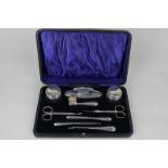 A George V cased silver manicure set in fitted case including a pair of silver topped glass jars,