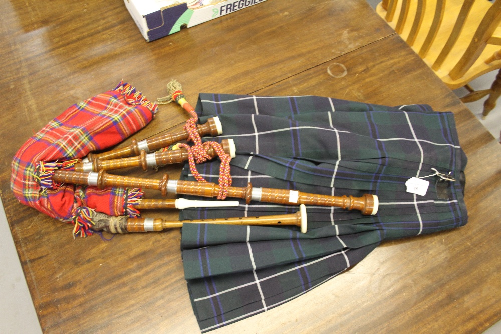 Scottish Highland kilt. Leather straps, metal buckles, size 32. Plus a pair of 'child's' bagpipes.