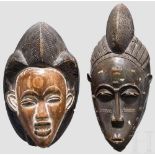 Zwei afrikanische Masken, 20. Jhdt. Holzgeschnitzt, teils patiniert. Höhen 39 cm und 33 cm. Zustand: