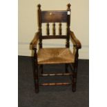 An American oak spindle back open armchair, with rush seat and double stretcher base