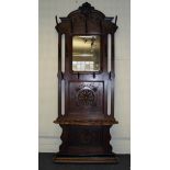 A late 19th century French oak hunting lodge hallstand, the scrolled shield pediment over a canted