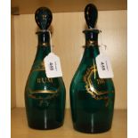 A pair of early 19th century green glass spirit decanters, each with flattened stopper, gilt