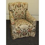 An Edwardian upholstered fireside armchair with floral linen covers