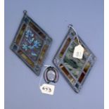 A pair of small lozenge form leaded, stained and painted glass panels, one decorated with branch and