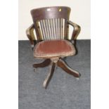 An early 20th century beech framed office swivel armchair, with lathe back, close studded seat,