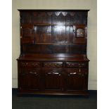 A 18th century-style oak tall dresser, the rack with moulded cornice and shaped frieze over two