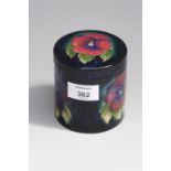 An early 20th century Moorcroft blue ground pottery powder jar and cover, decorated with a pink