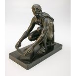 A 19th century bronze figure of a gentleman, in a flowing chiton crouching to sharpen his sickle