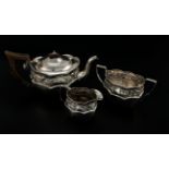 A late Victorian three piece silver tea set, shaped oval with a chased foliate band below