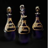Four late 19th century amethyst spirit decanters, each with flattened stopper variously decorated