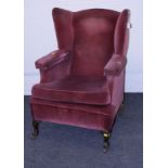 An early 20th century deep seated wing back armchair with red velvet stuffover upholstery