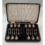 A cased set of twelve silver teaspoons and sugar tongs, with stylised pierced foliate terminals,