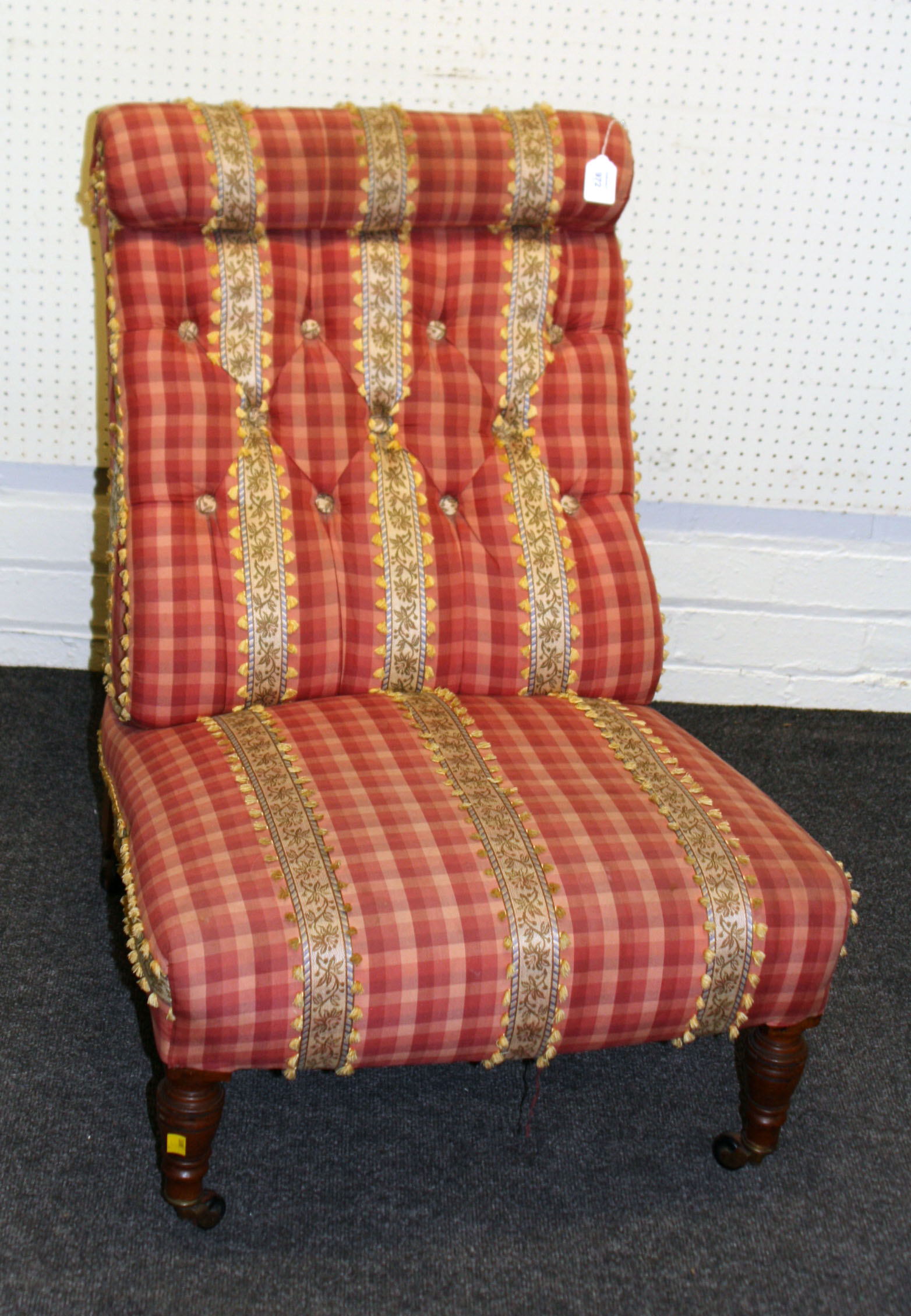 An Edwardian walnut framed nursing chair, later upholstered in applied stripe and tasselled