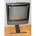 A 1992 Bang and Olufsen MX7000 television set on a black metal stand with remote control
