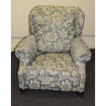 An early 20th century deep seated wing back drawing room armchair, with rolled arms, horsehair