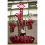 A Victorian cranberry glass epergne, the frilled dish base supporting three trumpet vases and twin