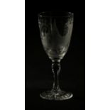 An Edwardian finely wheel etched wine goblet with detailed scenes of a church above a faceted stem