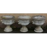 A set of three reconstituted stone garden urns of campagna form, each having a cherub and swag