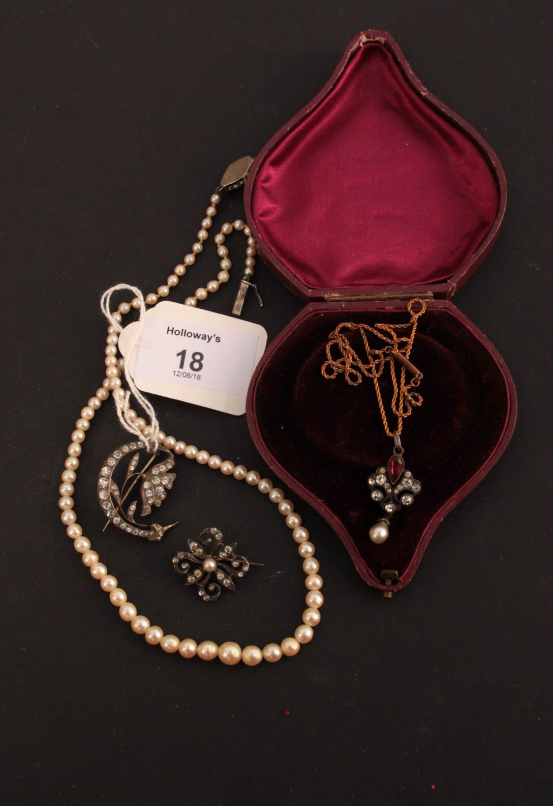 A paste set white metal scrolling pendant on chain, together with two paste brooches and a single