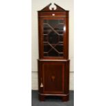 An Edwardian mahogany corner vitrine, the broken architectural pediment over a strung astragal