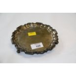 An Edwardian silver waiter, circular with raised pie-crust border, on three scrolling feet,