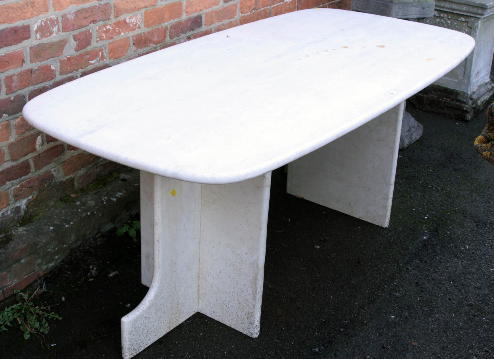 An Italian cream travertine conservatory patio dining table, the shaped rectangular top on twin
