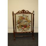 A late Victorian mahogany firescreen having a scrolling acanthus surmount above a glazed gros