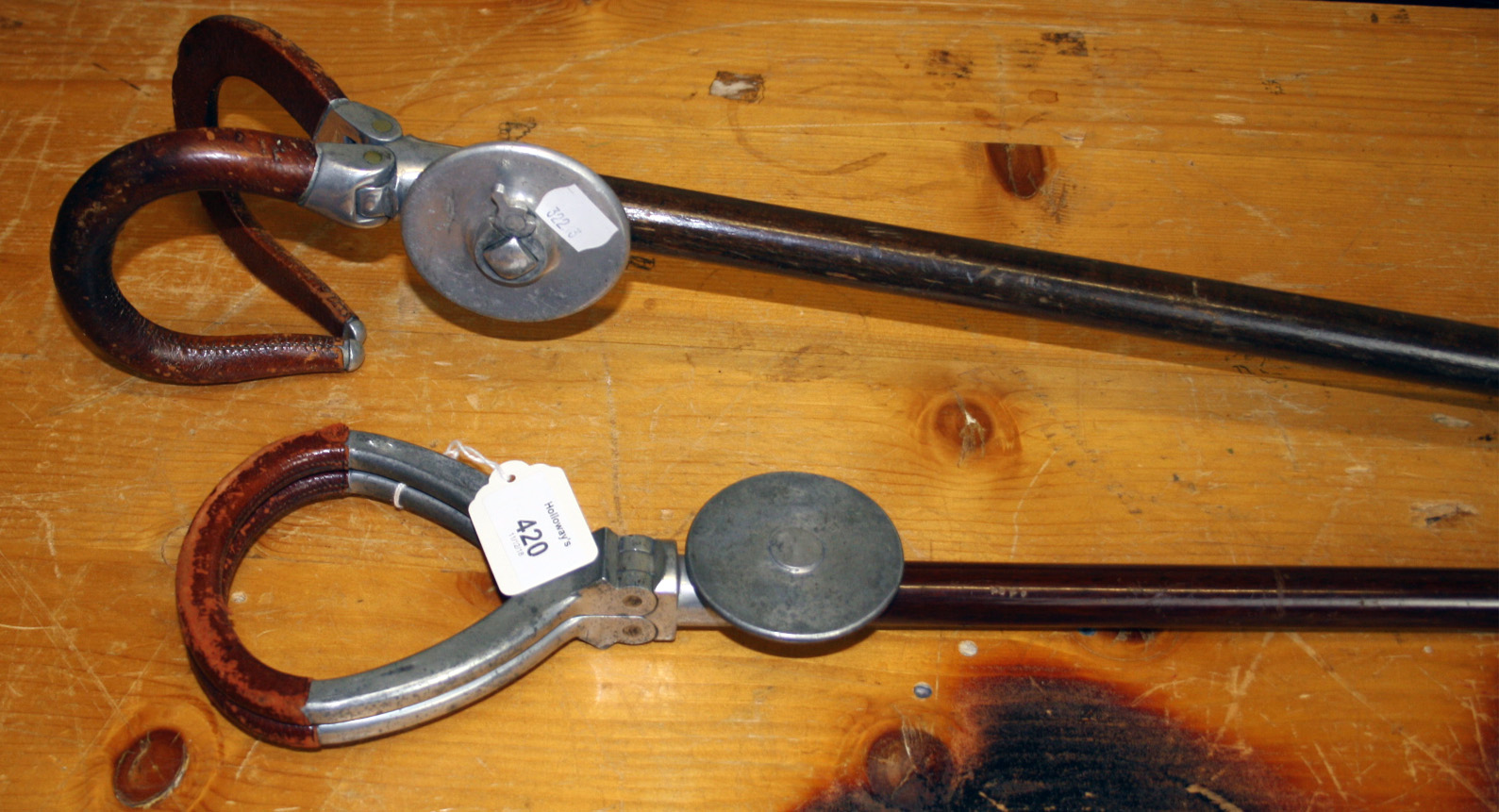 Two early 20th century shooting sticks, each with double hinged folding handle seat and detachable