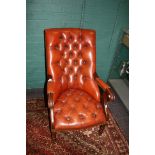 A 20th century red/brown button hide upholstered library armchair on ring turned forelegs and