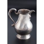 A substantial George III silver water jug, of baluster form with acanthus thumb piece to the swept