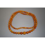 A string of graduated butterscotch amber coloured oval beads. Total length 107cm, largest bead 22mm,