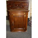 A late 18th century oak wall mounting corner cupboard, the moulded cornice over fielded panel door