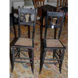 A pair of 19th century ebonised high backed music room chairs, each having lyre splat, cane seat