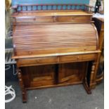 A reproduction hardwood roll top desk, having a spindle turned gallery over two frieze drawers and a