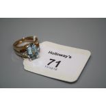 An aquamarine and diamond dress ring, the step cut aquamarine in raised claw mount, with two stone