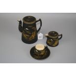 A 20th century Japanese Satsuma pottery coffee set with gilt river landscapes on a black background