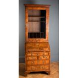 A George II figured walnut bureau bookcase, the moulded cornice over glazed door enclosing shelves
