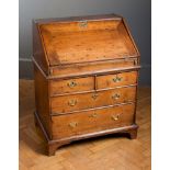 An 18th century oak bureau of small proportions, the mitred fall with pierced brass escutcheon