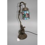 A Tiffany-style table lamp, the petal shade over a simulated bronze base cast with a young girl