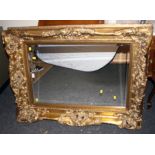 A large gilt composite wall mirror, the pierced frame moulded with acanthus scrolls and flowers