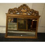 A gilt composite overmantel mirror with leafy scroll and flowering urn surmount over a bevelled