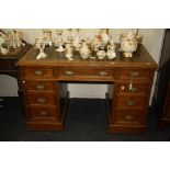 An Edwardian oak twin pedestal writing desk, the rectangular top with moulded edge, fitted a