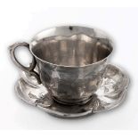 An early 20th century Chinese silver tea cup and saucer of lobed form, engraved with simple floral