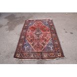 A Joshagan style rug with central diamond motif with flowering shrubs in a red ground within